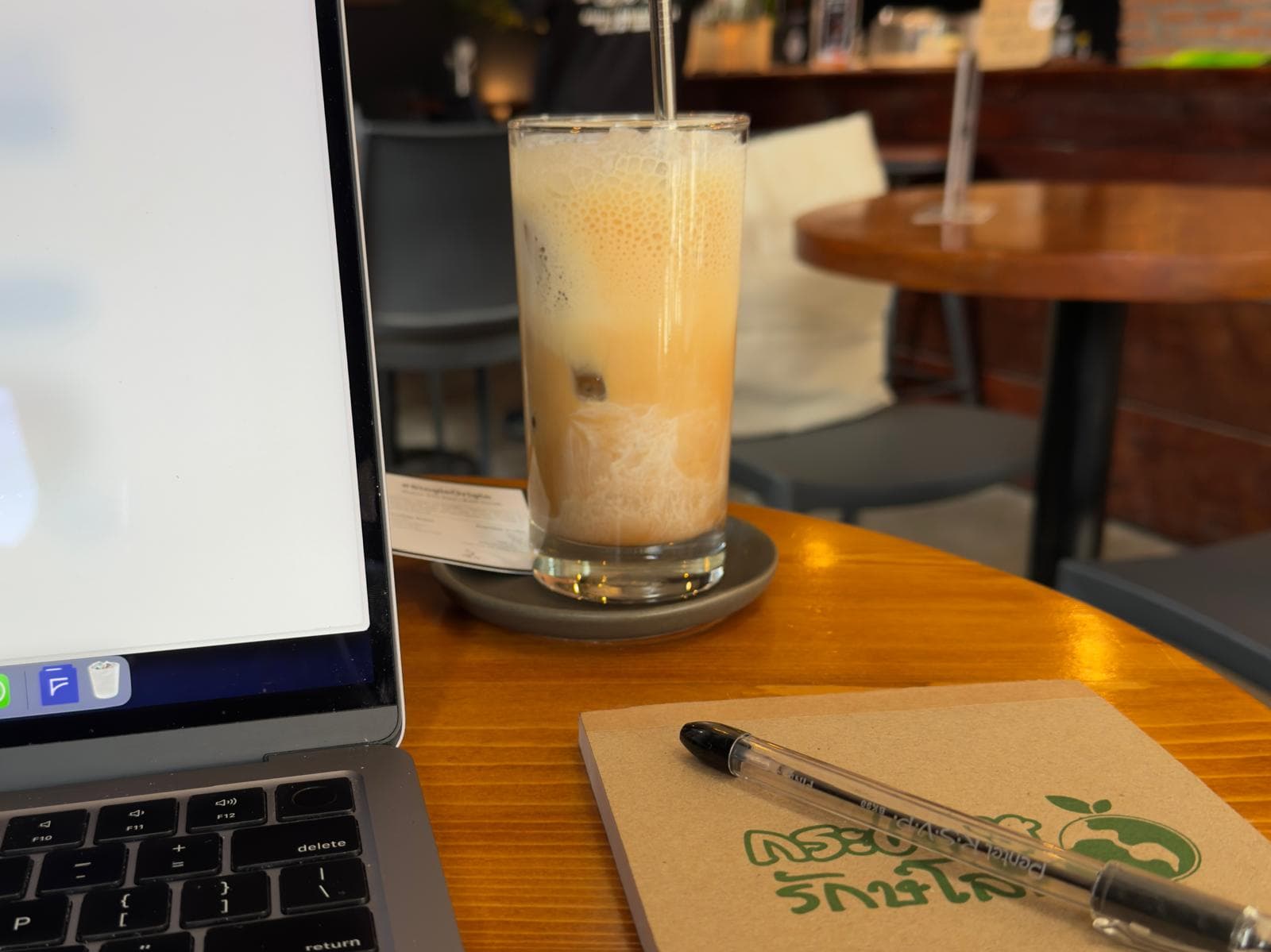 Remote work setup in a cafe with coffee, laptop, and notebook