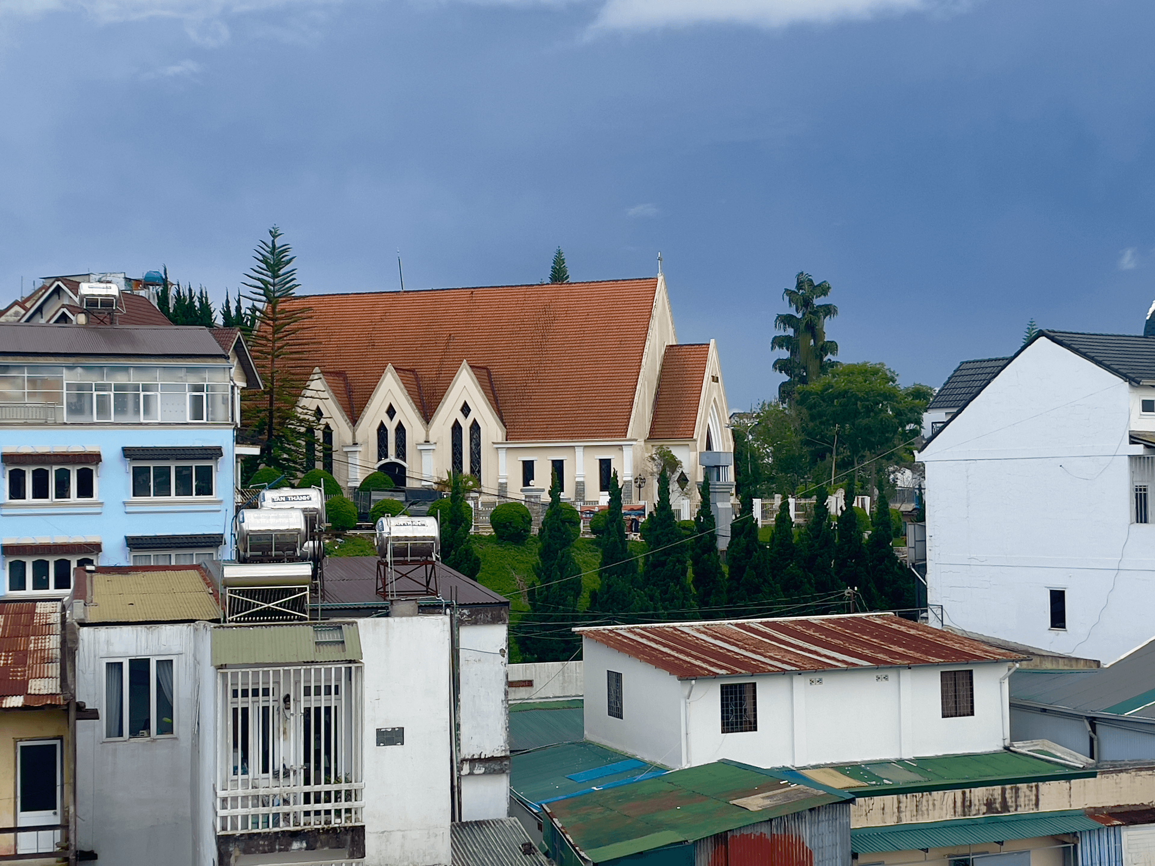 Church with an orange roof surrounded by colorful roofs and blue sky