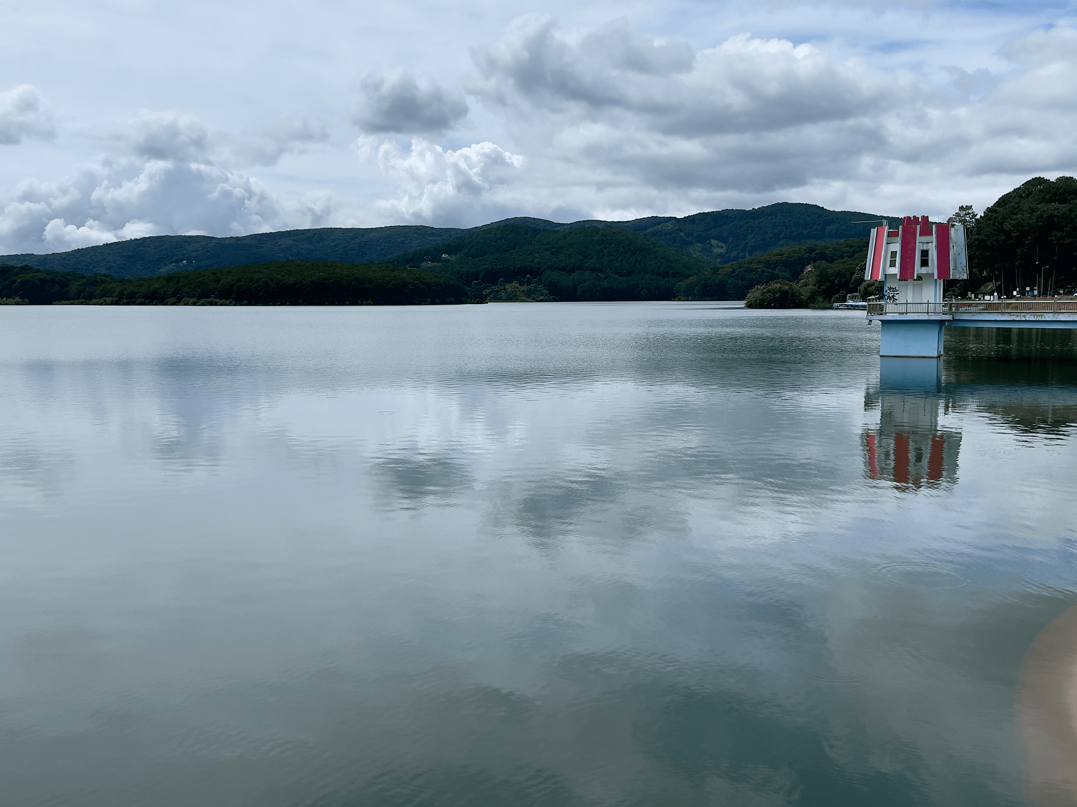 Calm lake in Da Lat with a red and white tower reflected in the water