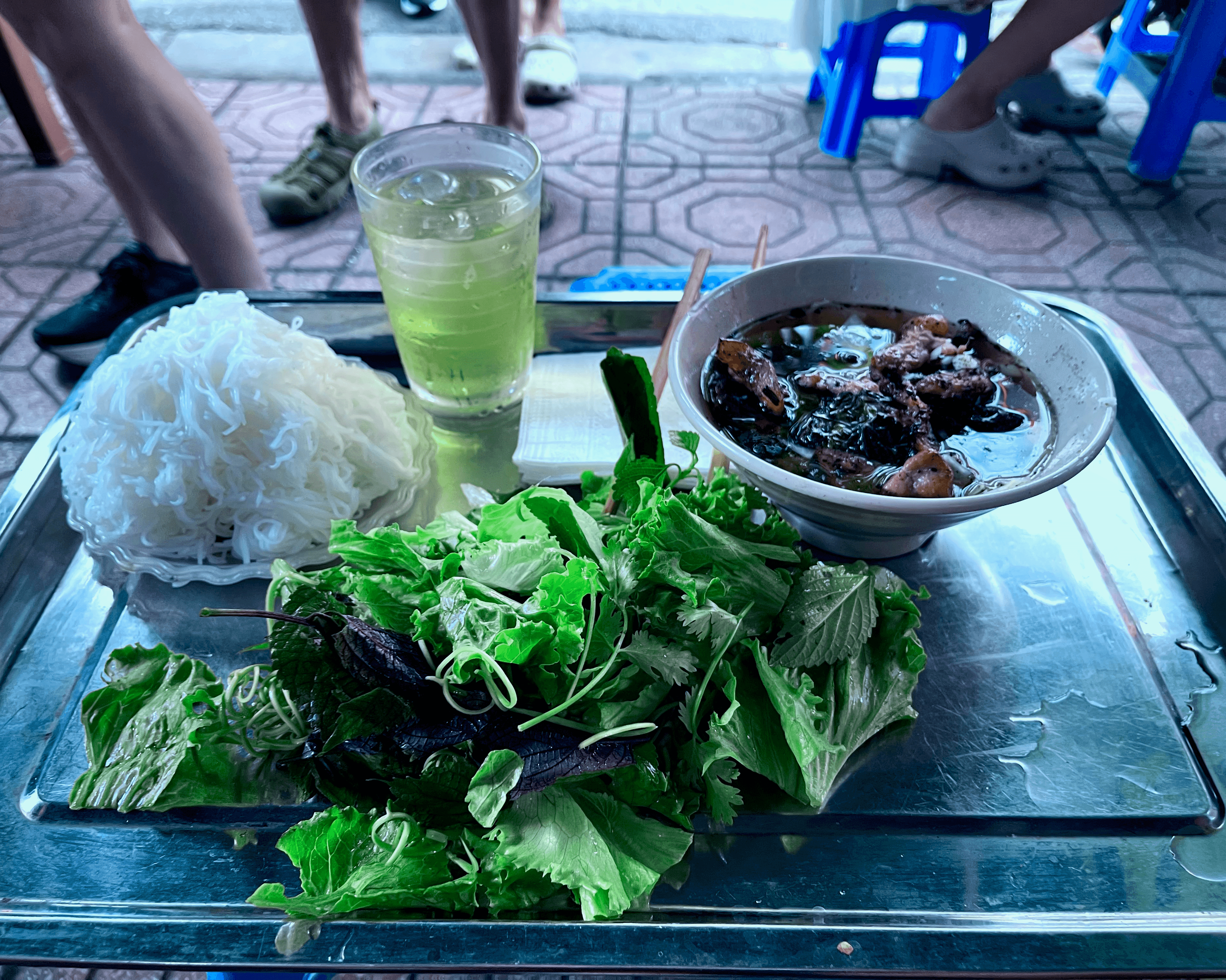 Tray with bún chả and iced tea on a sidewalk in Hanoi, Vietnam
