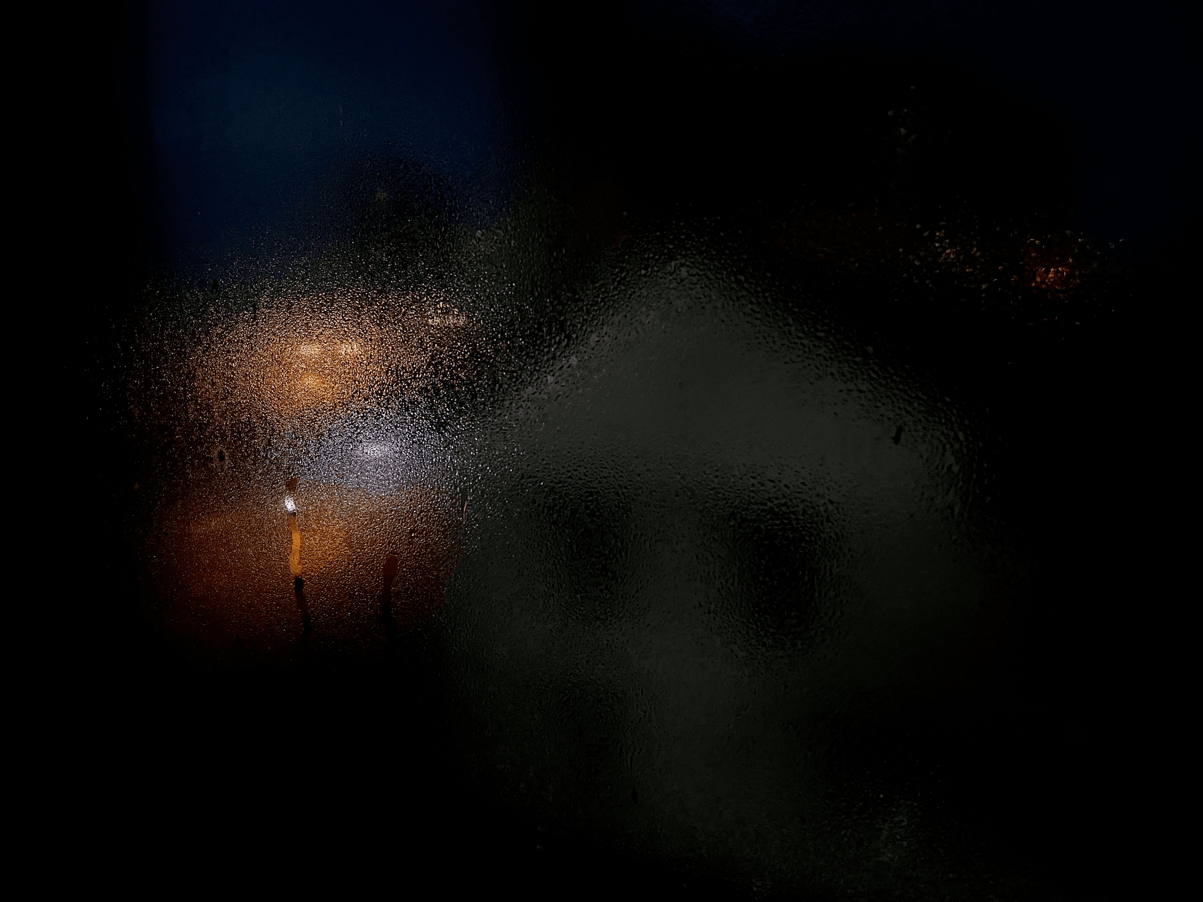Misty window with raindrops and a house in the background