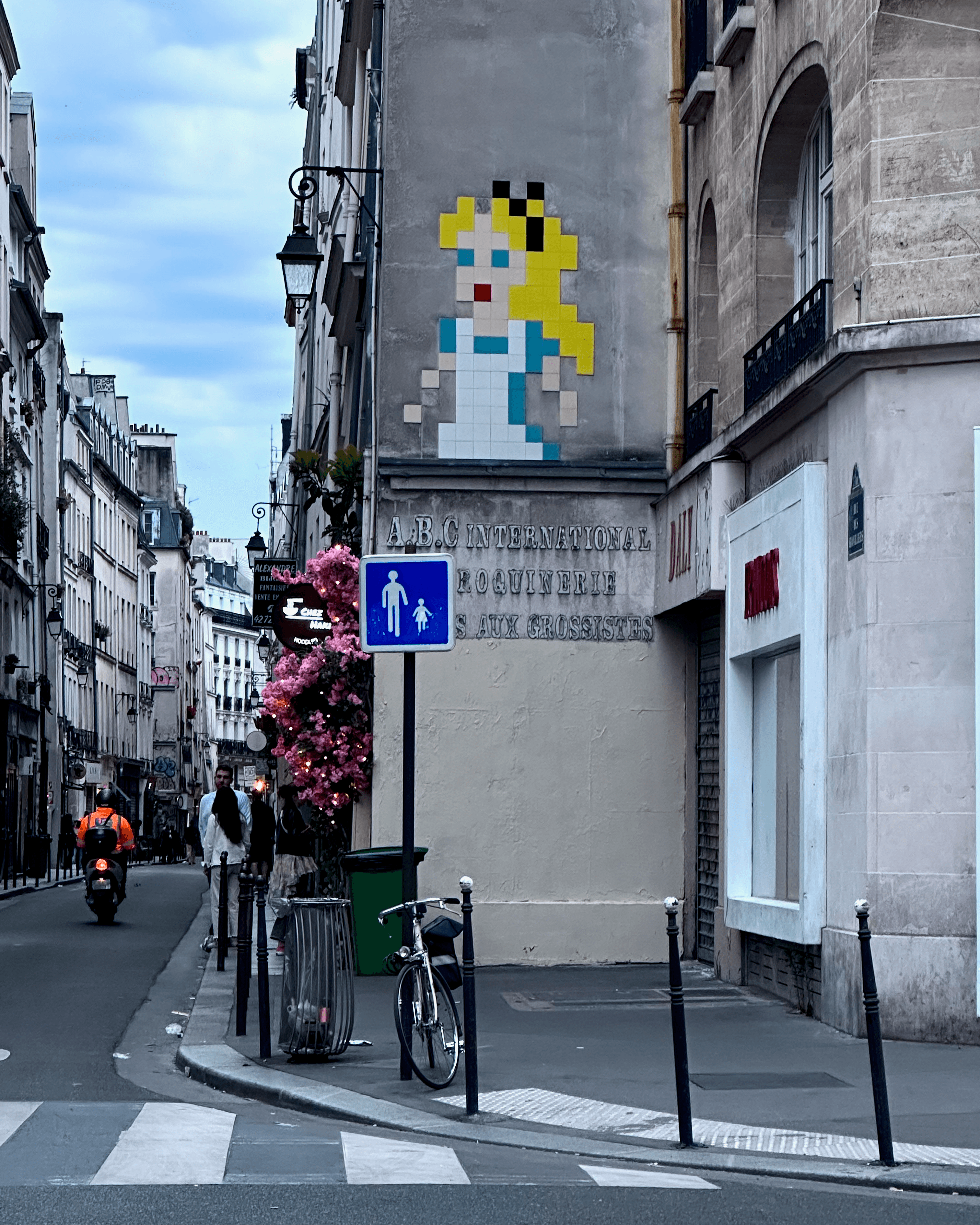 A street in Paris, France with people, bikes, art, and architecture