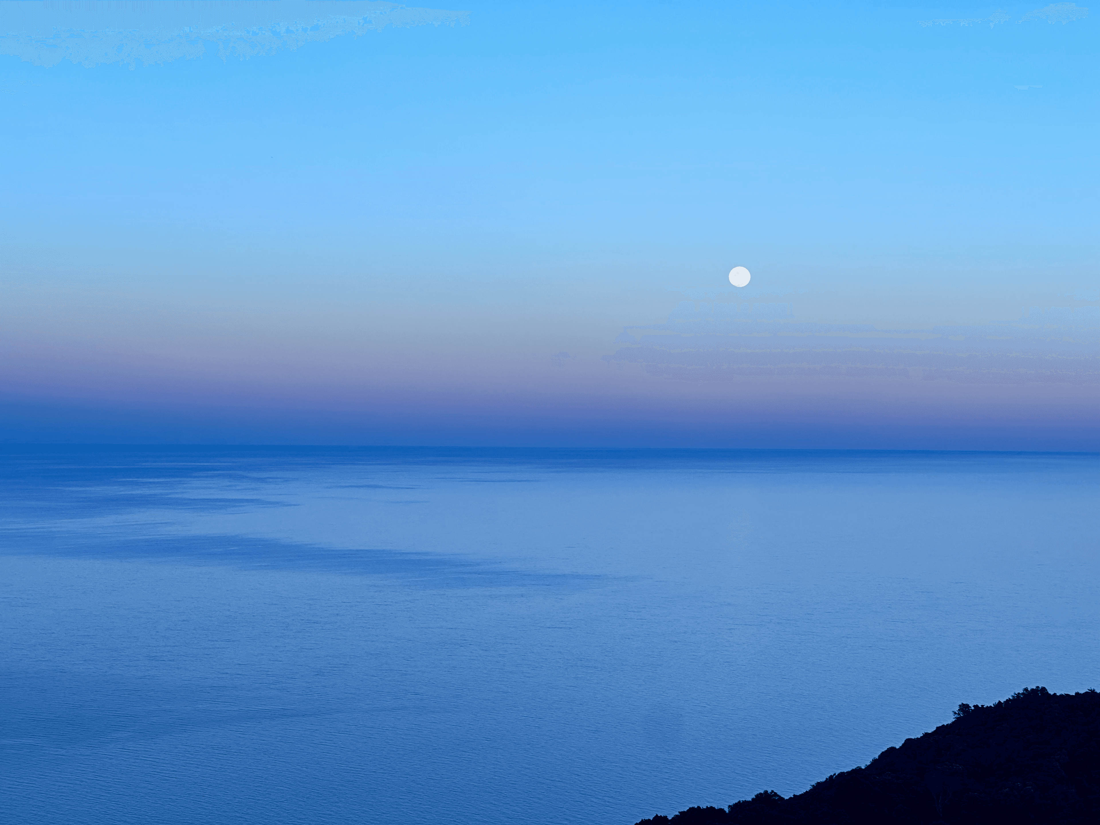 Mooon over a pink sky and blue ocean on Koh Tao, Thailand