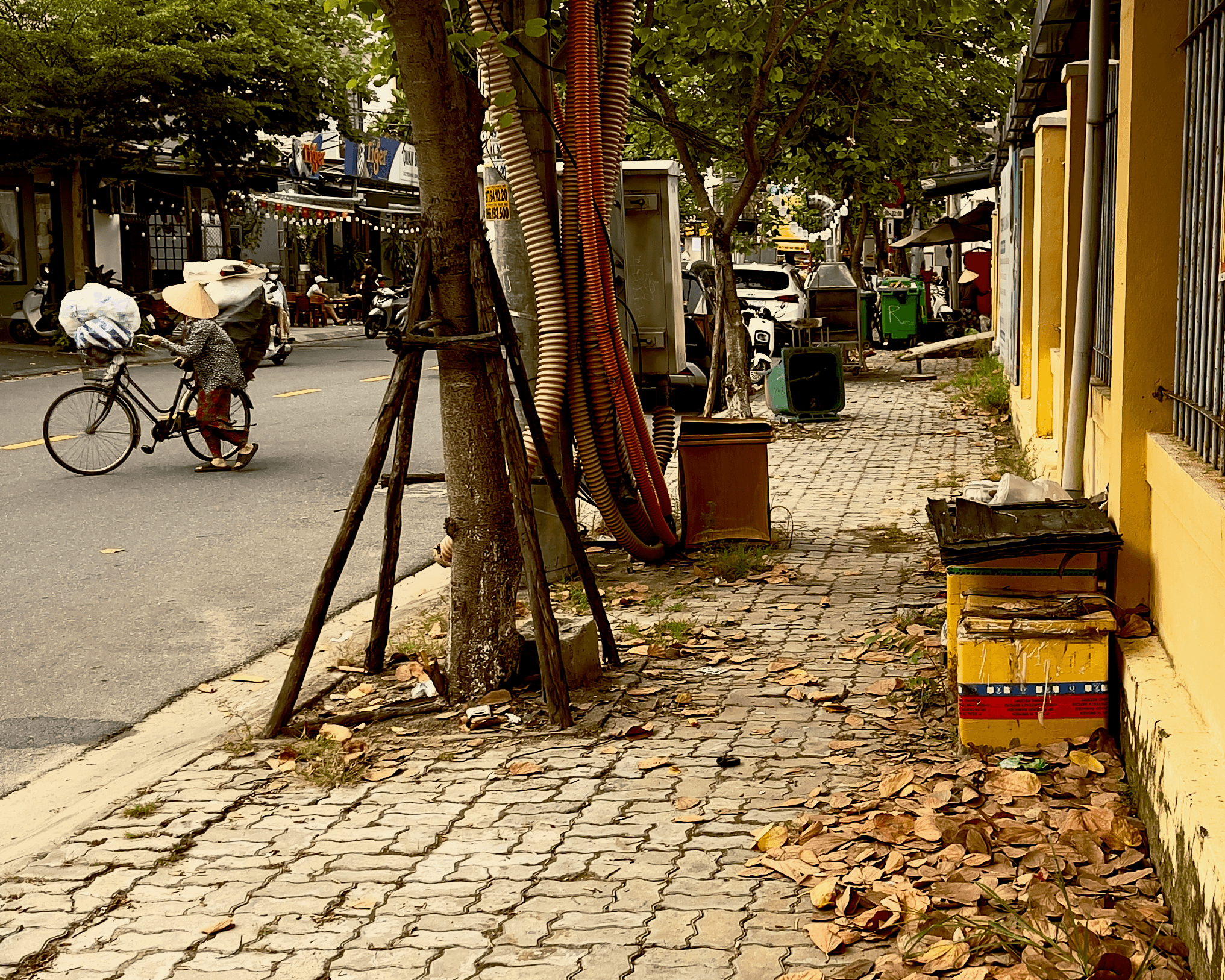 A street scene in Da Nang, Vietnam with a woman, bikes, and sidewalk